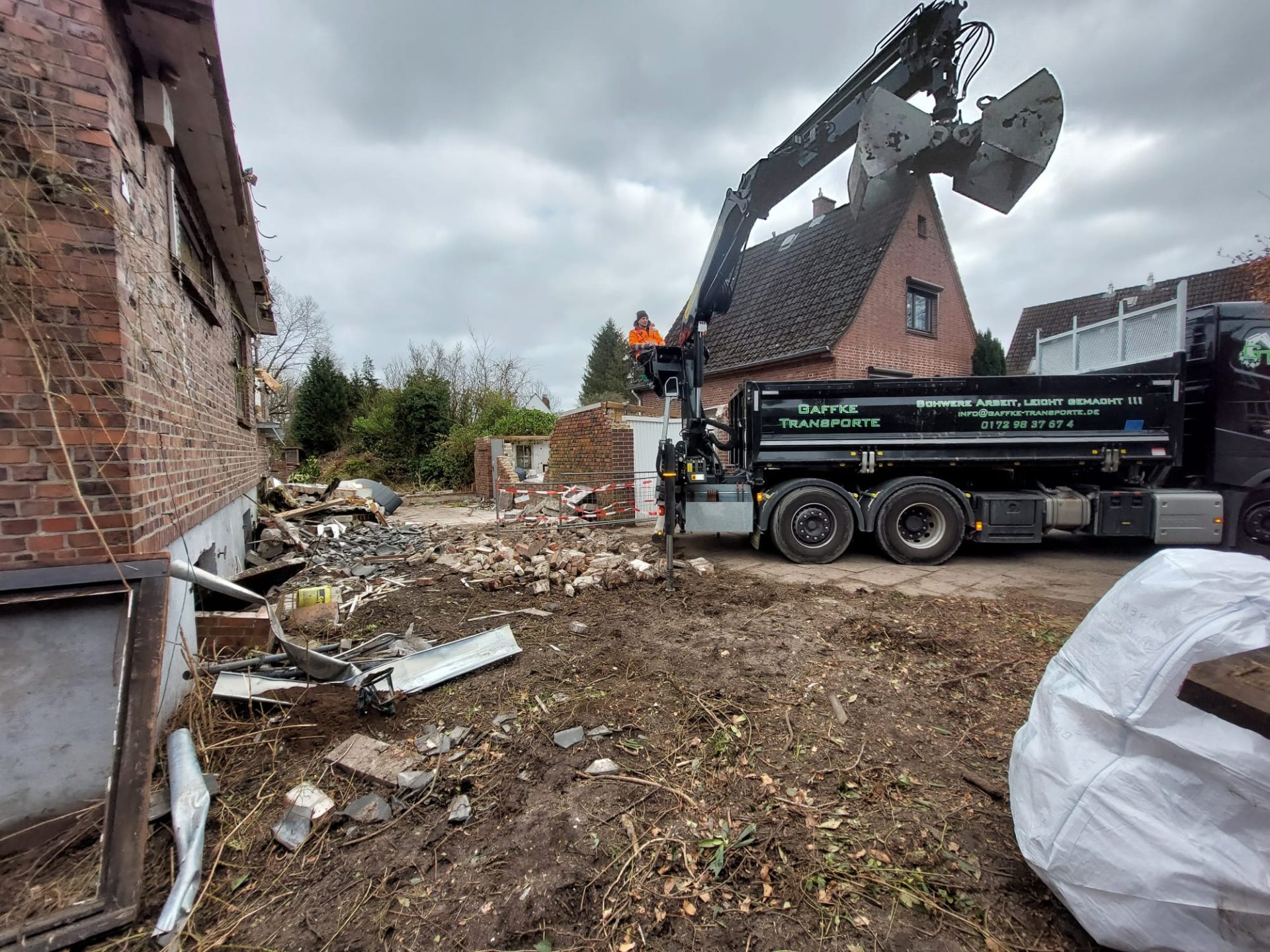 Schwarzer Greifer-LKW bei Abrissarbeiten auf einer Baustelle